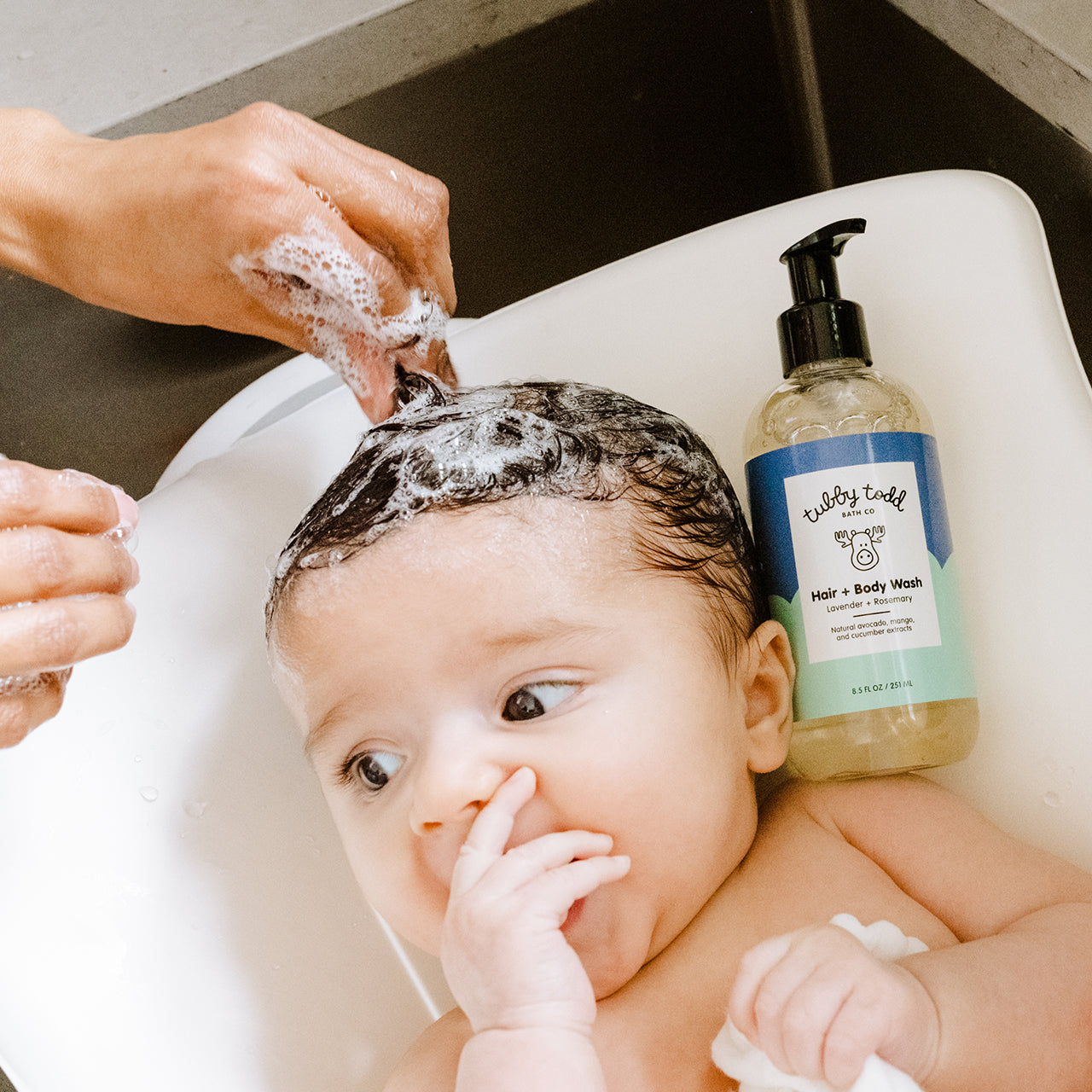 Mom washing her baby's hair using Lavender Rosemary Hair Body Wash 8.5oz in the sink.